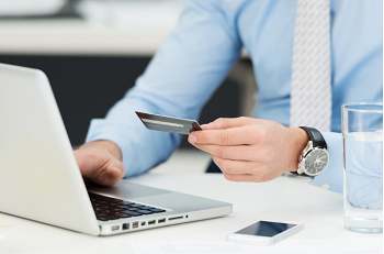 photograph of a person holding a card while using the laptop