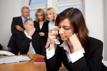 image of a crying businesswoman while her coworkers at the back gossiping