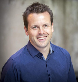 Man in a blue polo shirt smiling in front of the camera