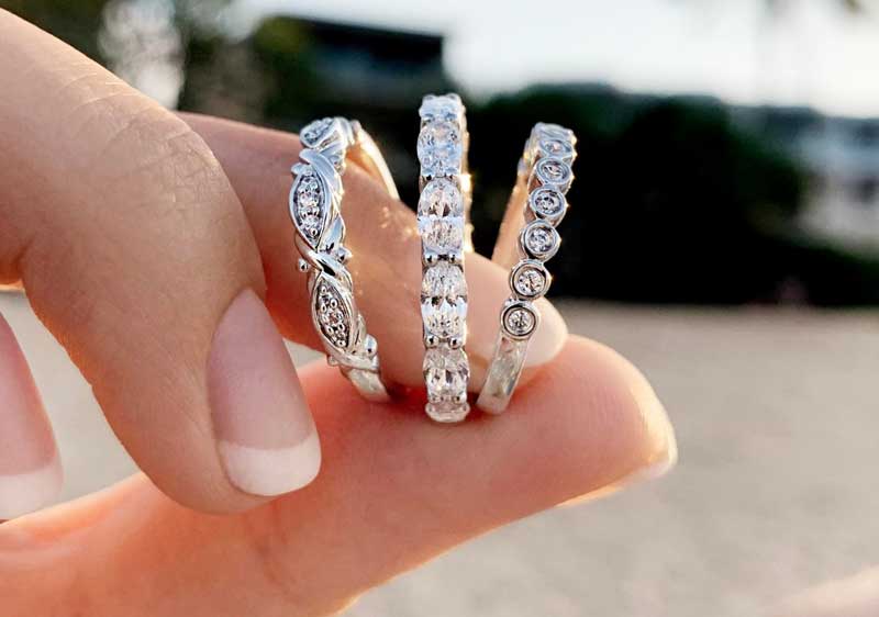 Three diamond rings held in the hand of a woman.