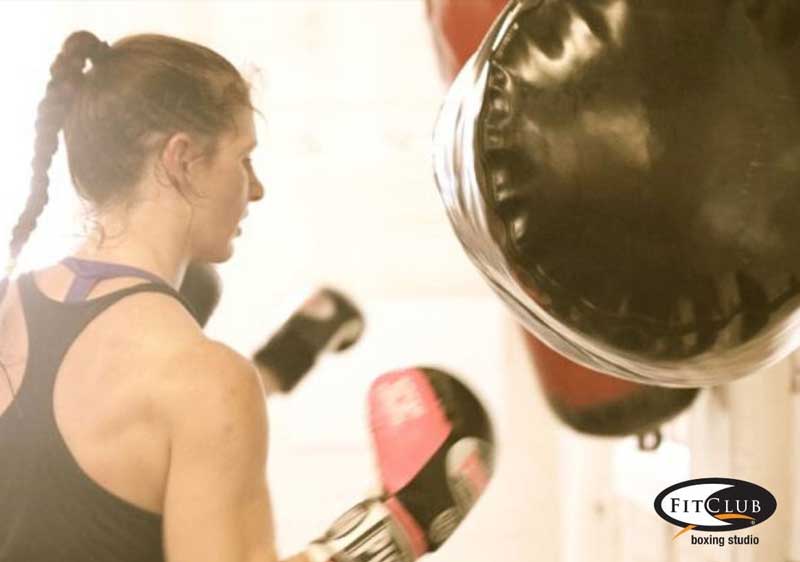 Woman in a gym punching a heavy bag during a workout