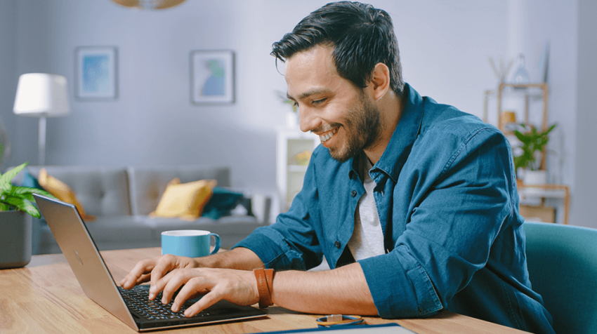 A man with a joyful smile sitting in front of his laptop computer