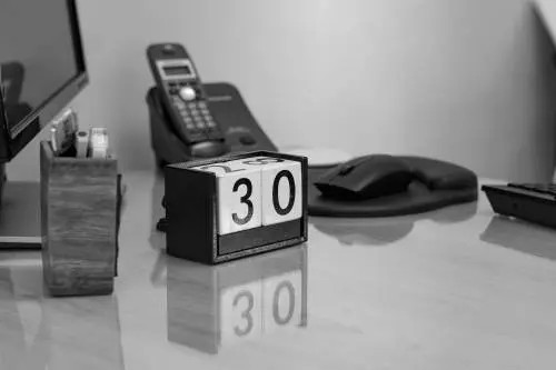 Image of a cube with the number 30, an old cellphone, a computer mouse, and a calculator arranged on a table.