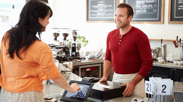 Image of a cafe owner and a cashier working together, representing teamwork and collaboration in a cafe setting.