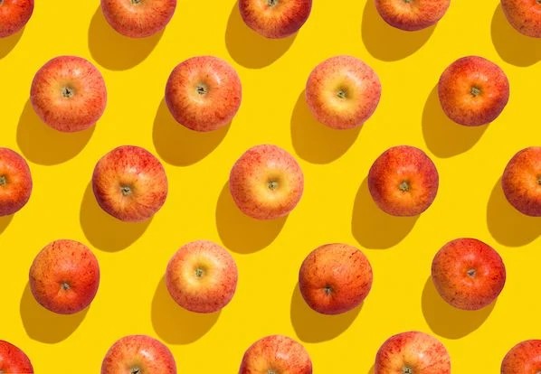Image of multiple apples on a yellow background.