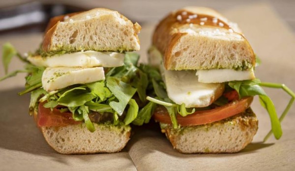 A sandwich split in half with cheese and fresh vegetables inside